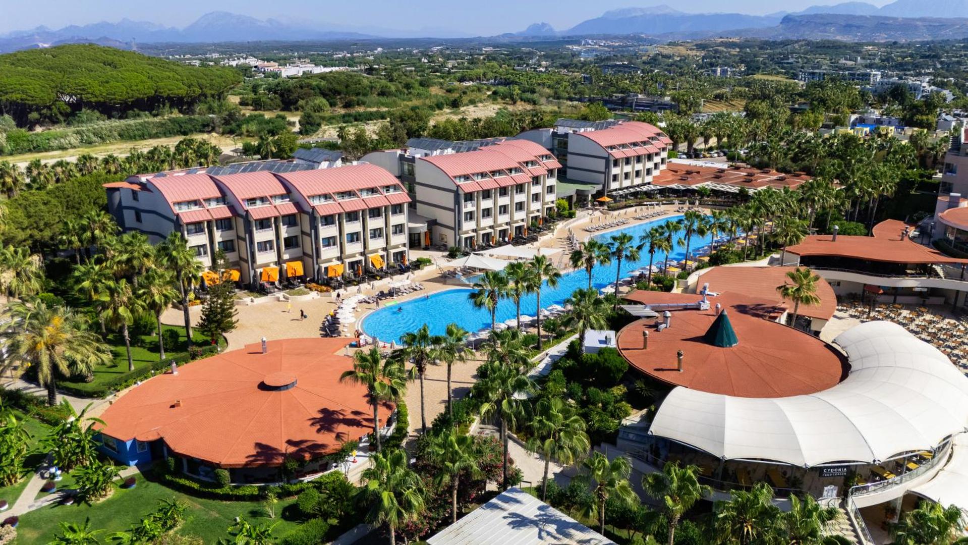 VONRESORT Elite viesnīcas teritorija Sidē no putna lidojuma — liels āra baseins, palmas un viesnīcas korpusi ar sarkaniem jumtiem