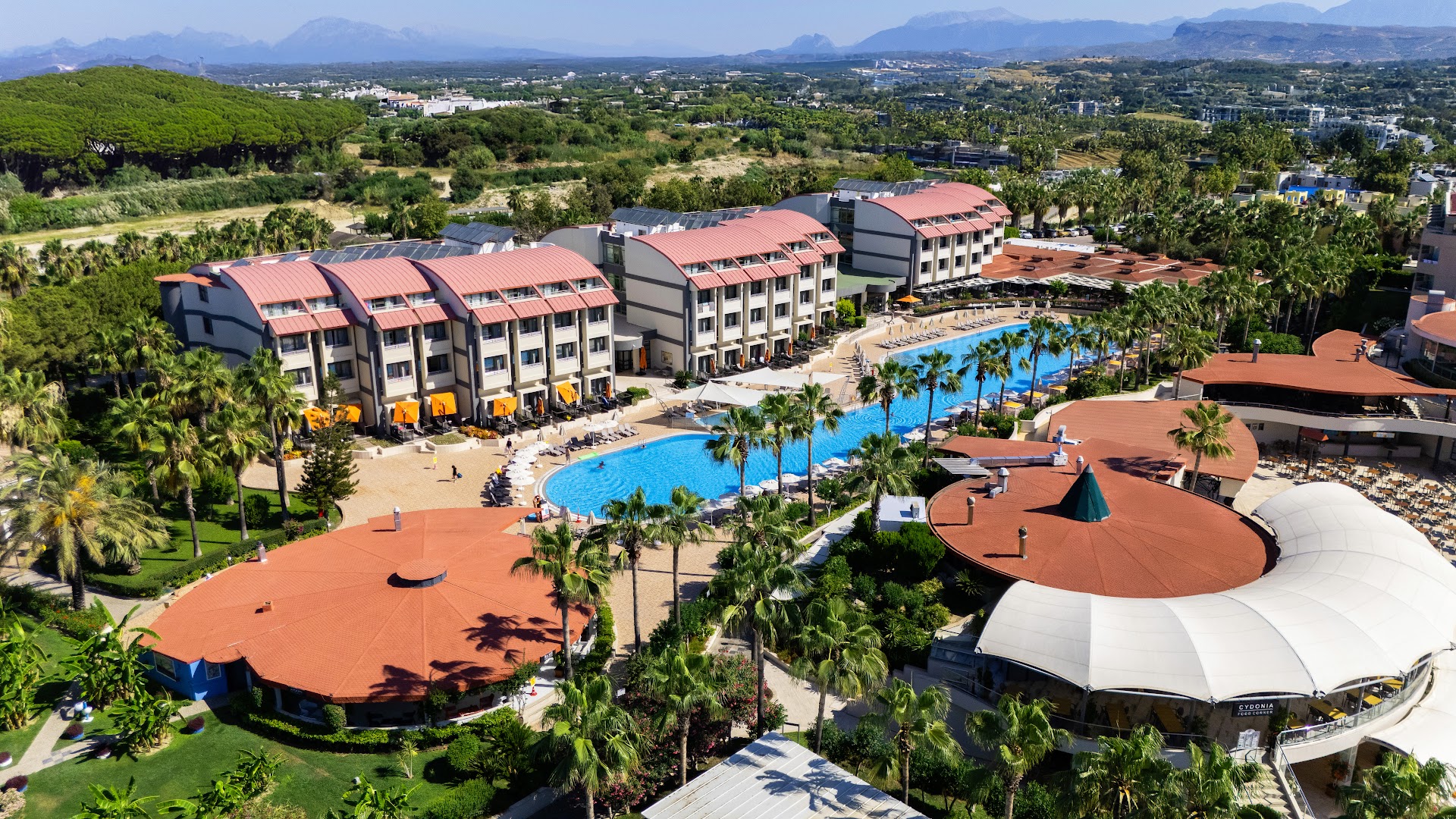 VONRESORT Elite viesnīcas kopskats ar baseinu, restorānu zonām un apkārtnes kalniem fonā saulainā dienā