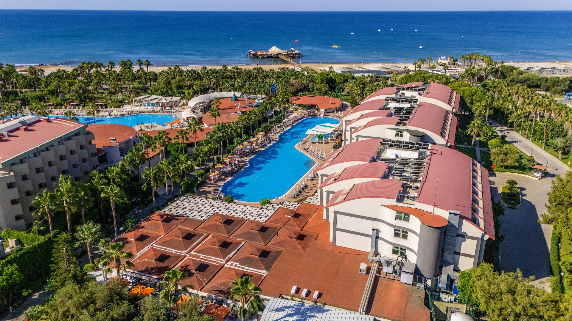 VONRESORT Elite skats no augšas uz baseinu zonu un Vidusjūras piekrasti — pludmale ar piestātni un viesnīcas ēkas