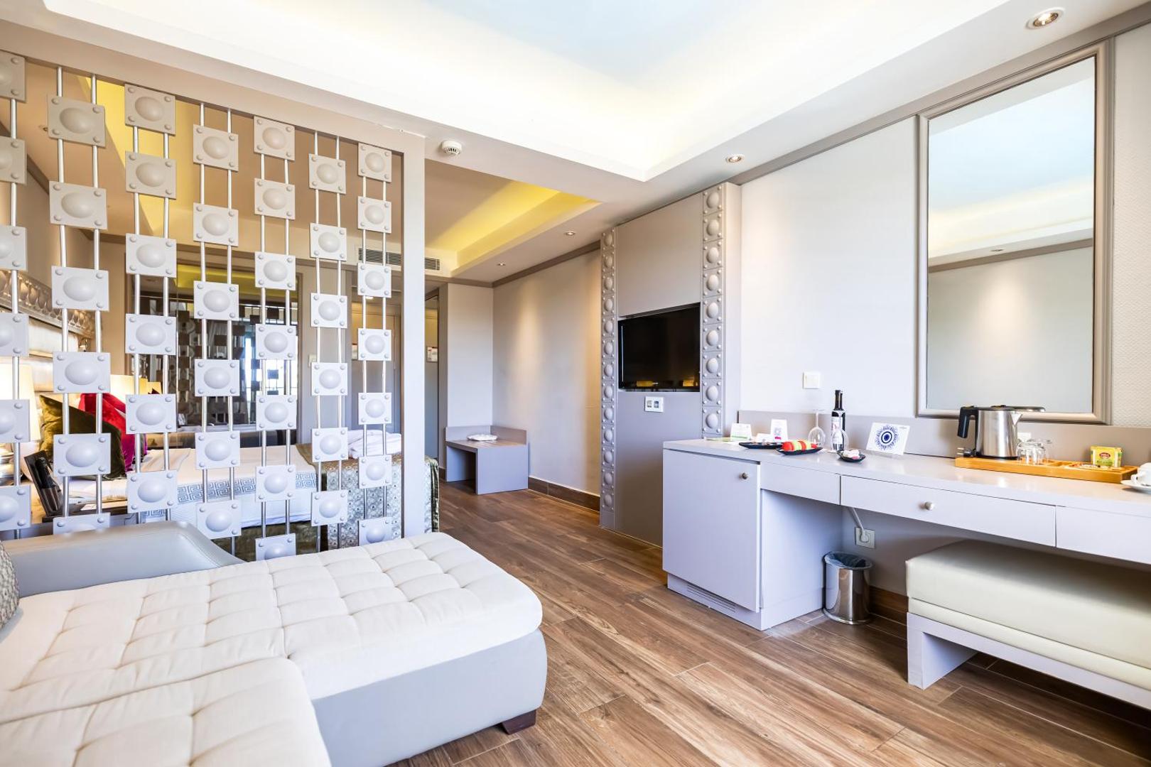 Vonresort Elite numura atpūtas zona ar dīvānu, darba galdu, televizoru un dekoratīvu starpsienu gaišos toņos