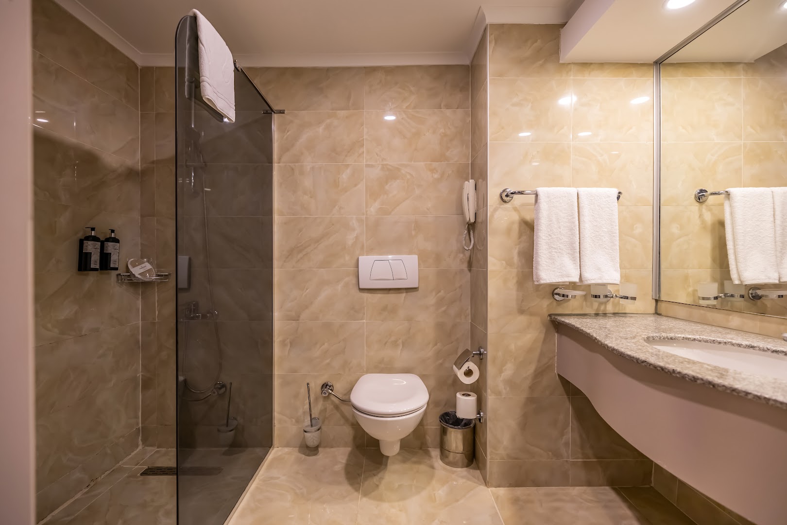 Vonresort Elite numura vannas istabas interjers ar dušas kabīni, gaišām flīzēm un higiēnas piederumiem Side reģionā
