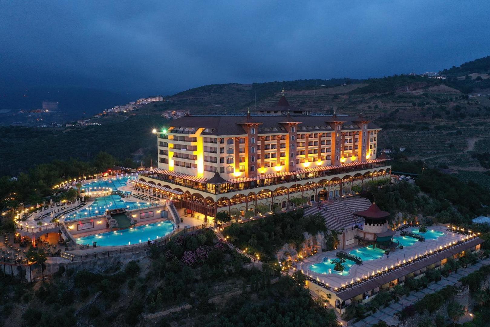 Utopia World Hotel vakara apgaismojums un izgaismoti āra baseini — nakts skats uz viesnīcas fasādi un atpūtas zonām