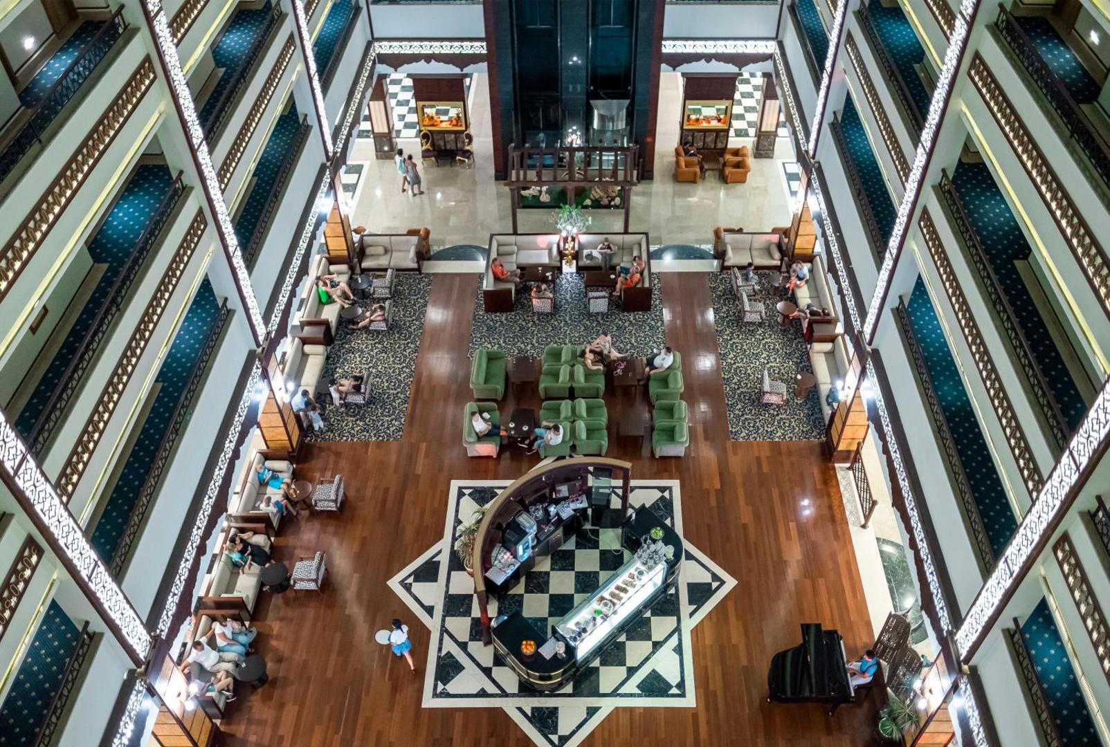 Utopia World Hotel plašais lobby bārs un atpūtas zona ar augstiem griestiem un klasisku interjeru — skats no augšas