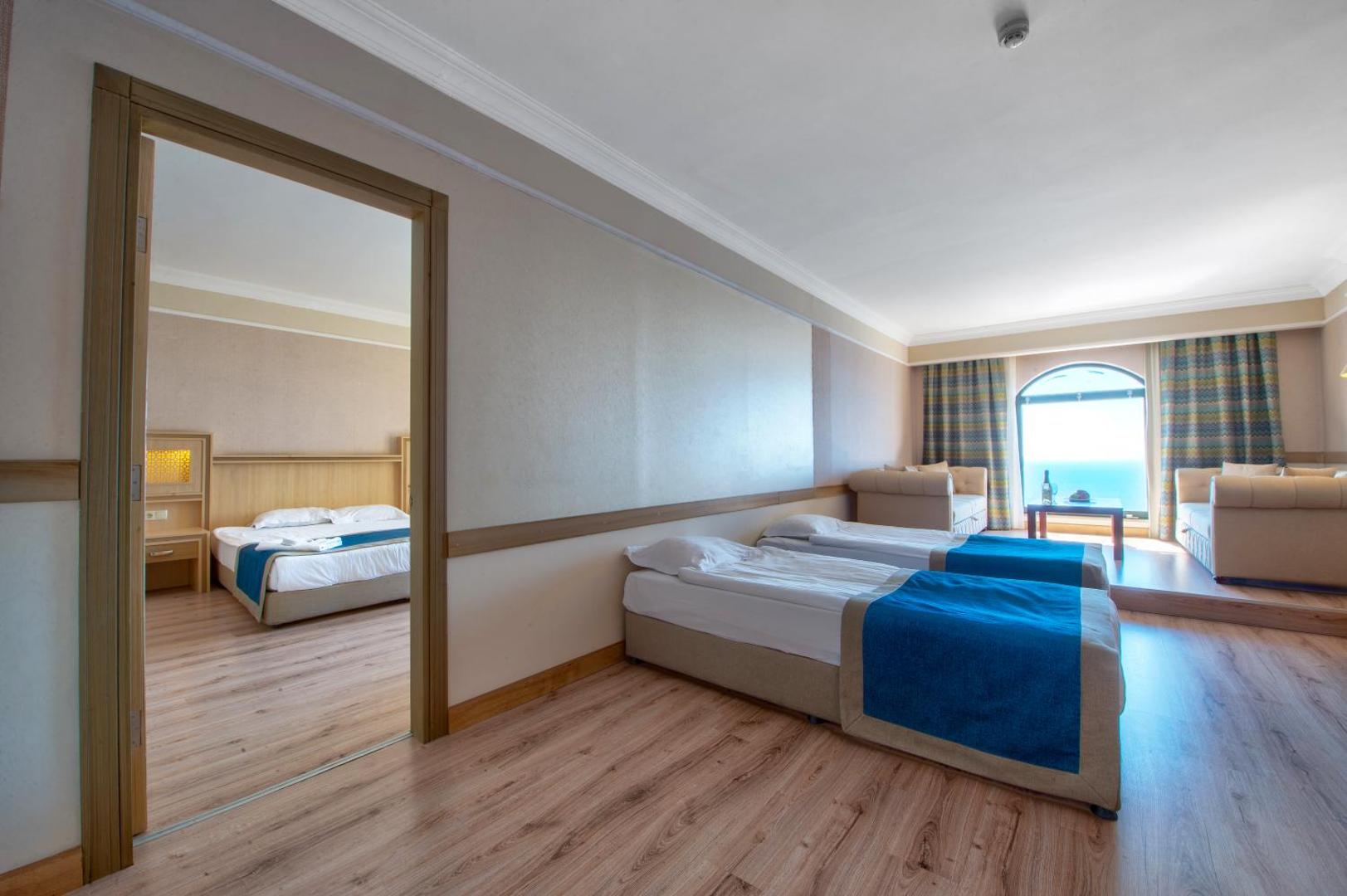 Utopia World Hotel ģimenes numurs ar divām atsevišķām istabām, gaišu interjeru un skatu uz jūru Alānijas piekrastē.