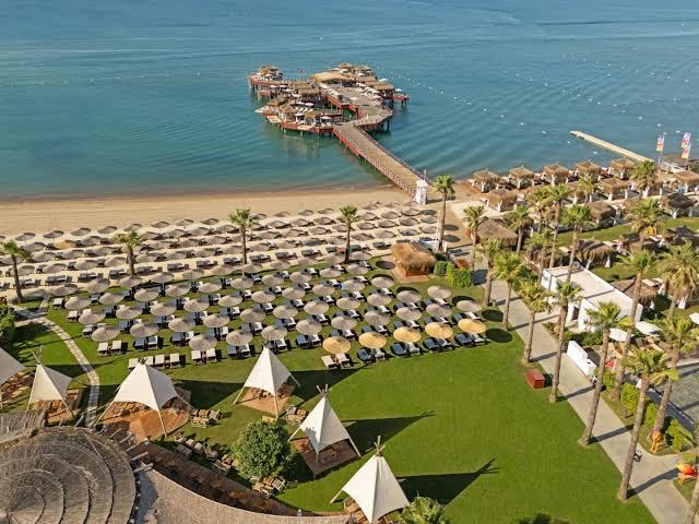 Aerofoto skats uz Titanic Mardan Palace plašo piekrastes zonu, lielu koka piestātni ar atpūtas vietām, palmu dārzu un saulessargu zonu