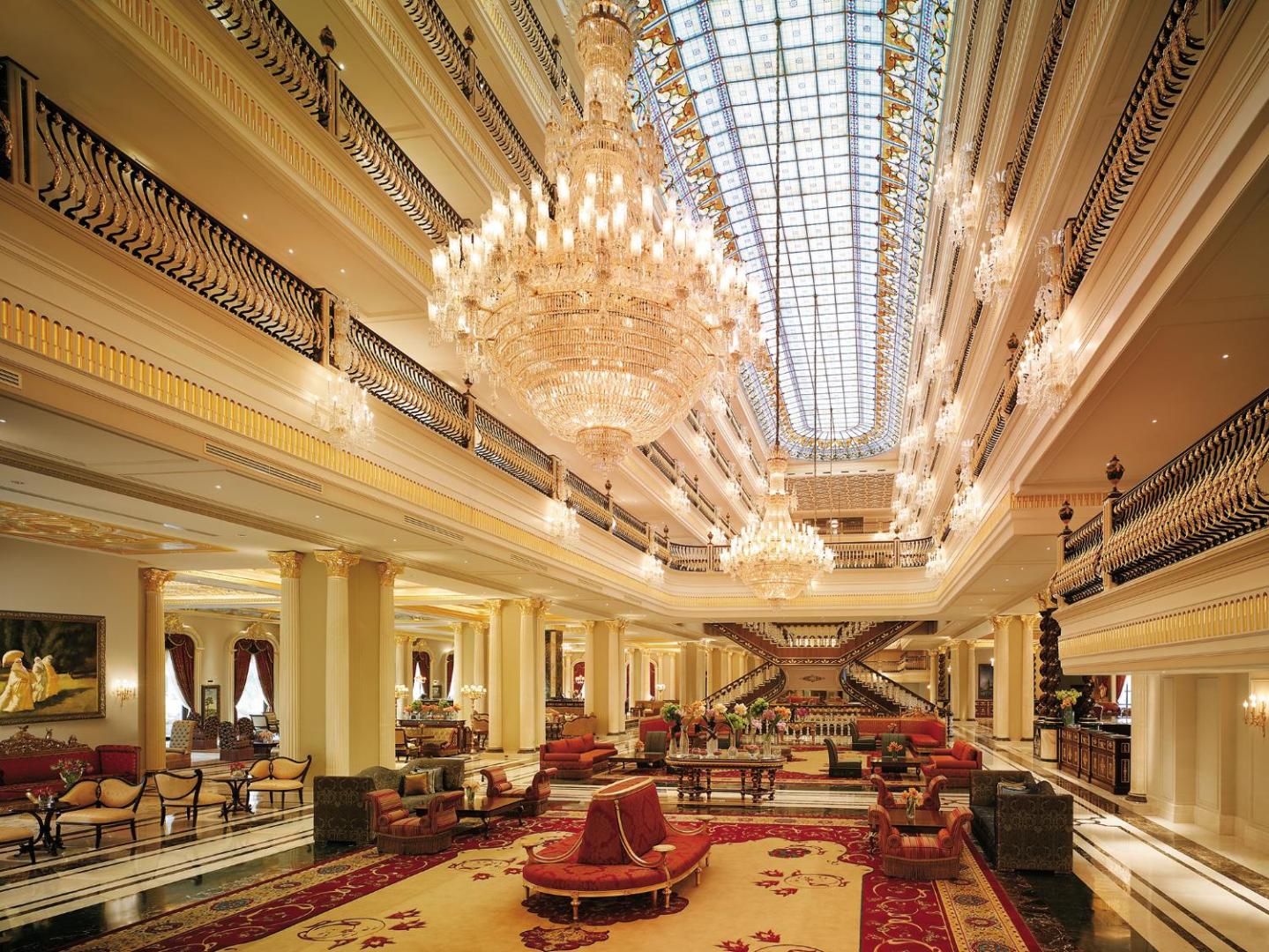 Titanic Mardan Palace greznais viesnīcas vestibils ar milzīgām kristāla lustrām, augstiem griestiem, zeltītiem dekorācijām un sarkanu paklāju atpūtas zonā