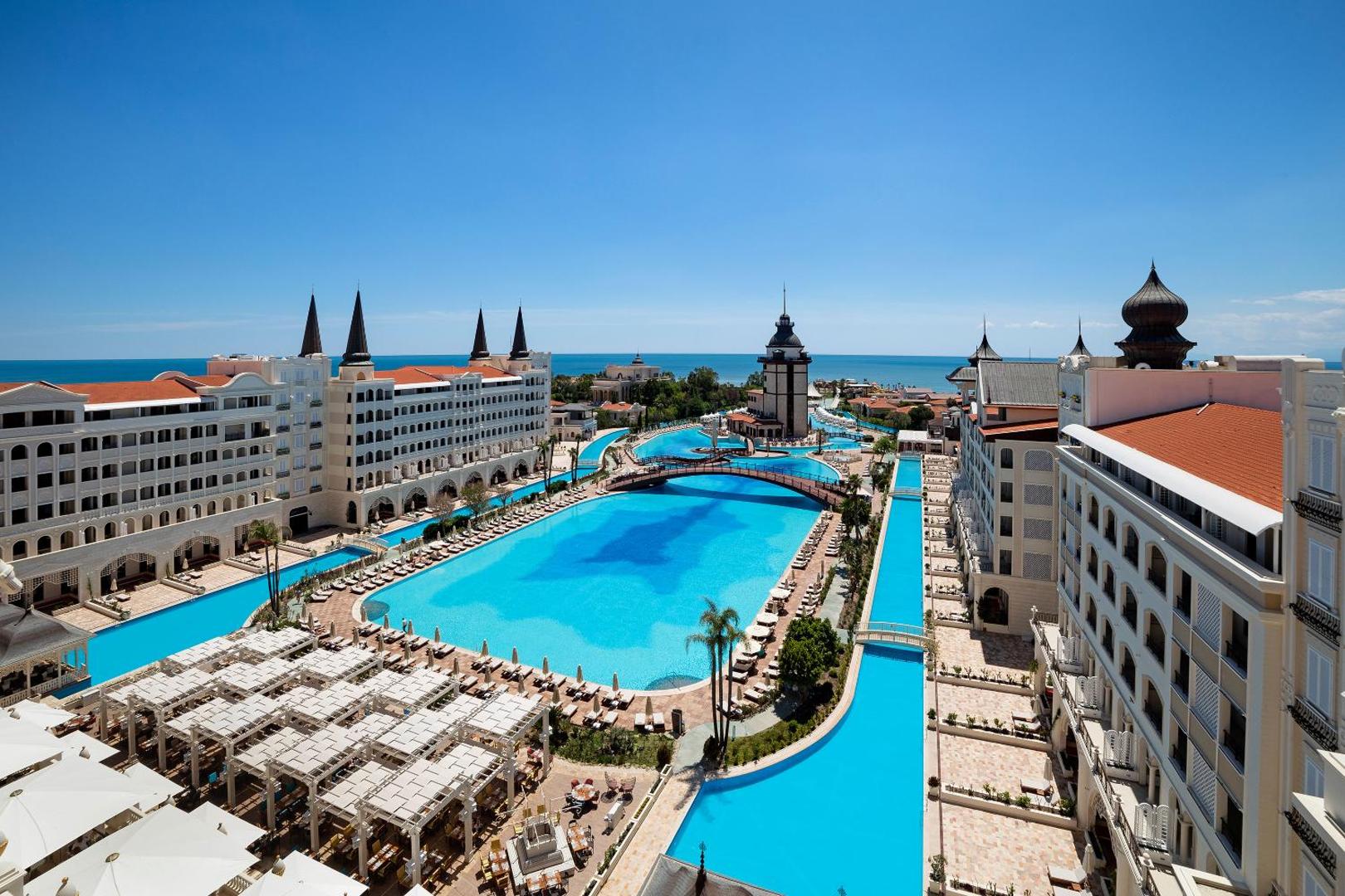Titanic Mardan Palace viesnīcas panorāmas skats uz plašajiem baseiniem, tiltiņiem un pils arhitektūru Antaljā, Turcijā