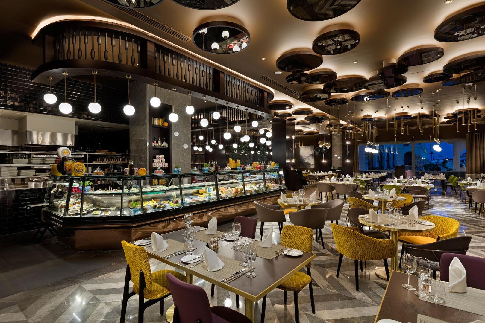 Titanic Mardan Palace elegants restorāns Antaljā ar bagātīgu uzkodu bufeti, modernu apgaismojumu un stilīgiem dzelteniem un violetiem krēsliem