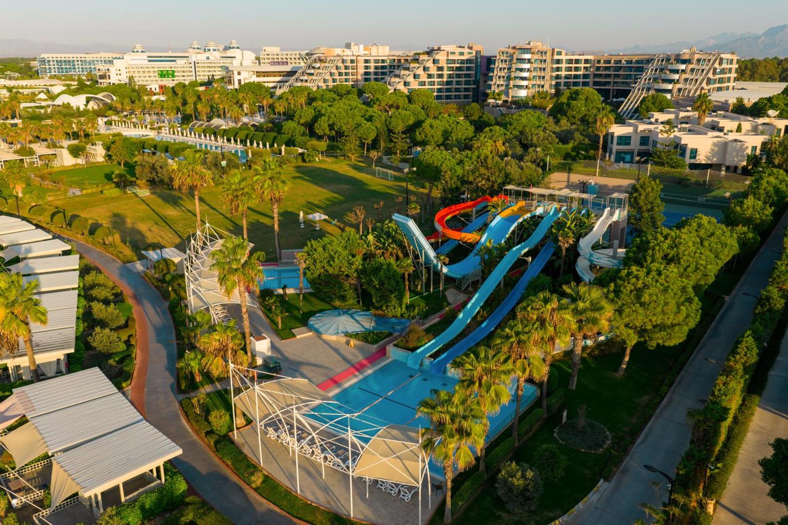 Susesi Luxury Resort akvaparks ar vairākiem krāsainiem ūdens slidkalniņiem, baseinu un sauļošanās zonu, ko ieskauj palmas un priežu mežs