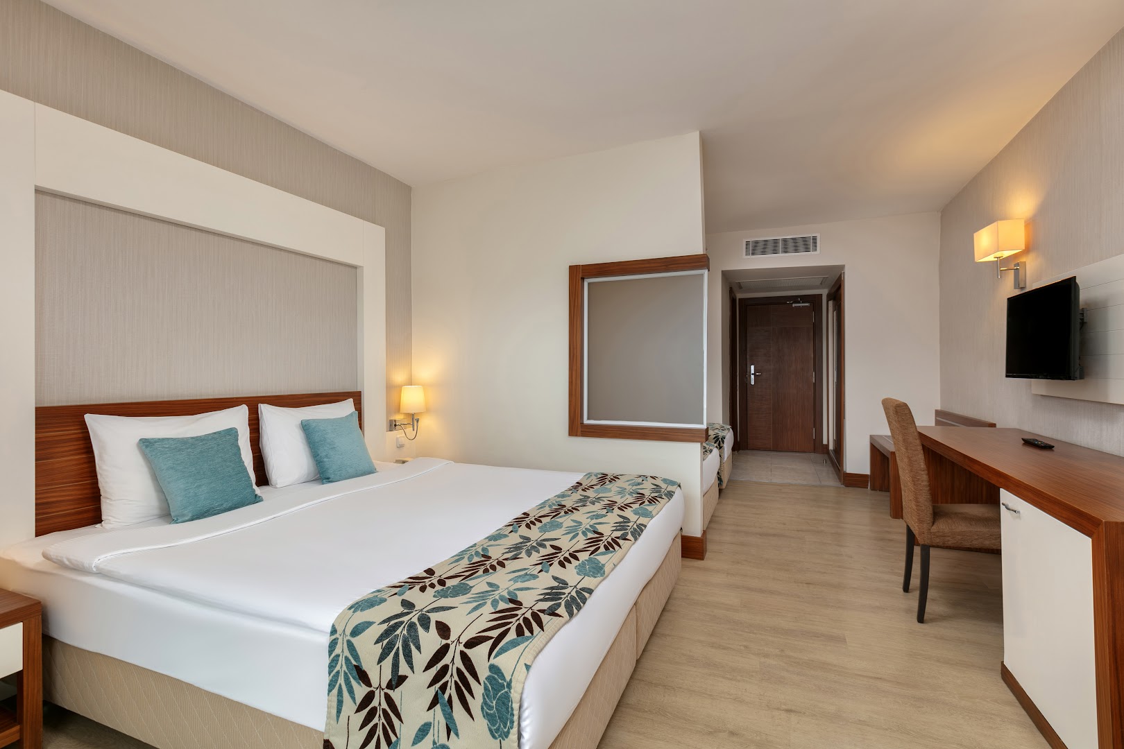 Greenwood Kemer Resort standarta numurs ar lielu divguļamo gultu, darba zonu un siltu apgaismojumu Kemeras piekrastē.