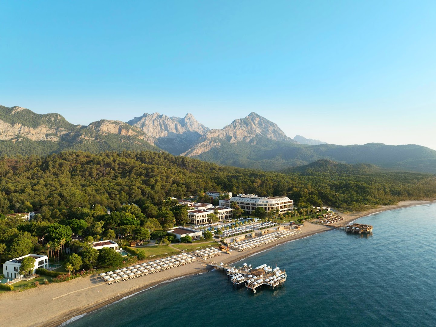 Plaša Sherwood Exclusive Kemer panorāma ar pludmali, piestātnēm, viesnīcas korpusiem un priežu mežu kalnu pakājē