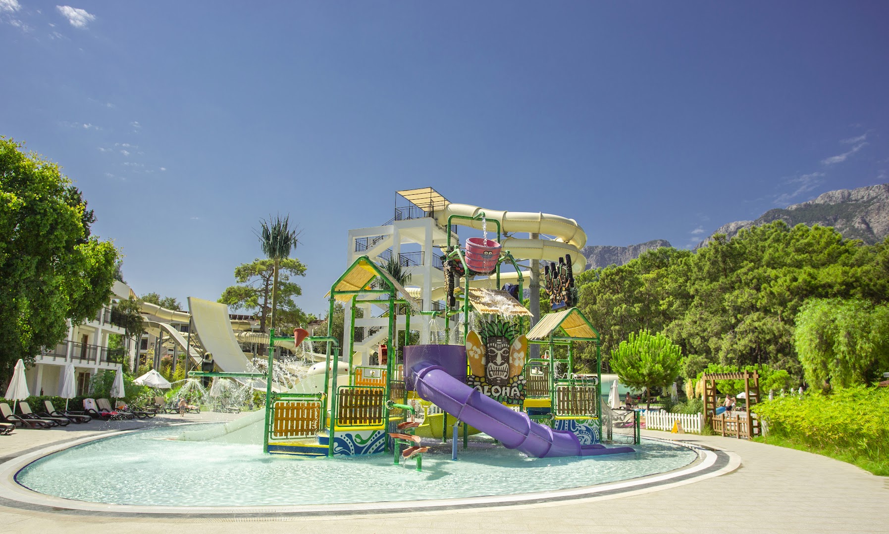 Sherwood Exclusive Kemer akvaparks ar krāsainiem slidkalniņiem un ūdens atrakcijām bērniem Kemeras reģionā, Turcijā — apkārtnē kalni un priežu mežs