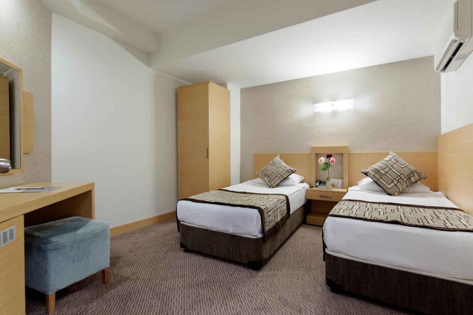 Saphir Resort & Spa numurs ar divām atsevišķām gultām, rakstāmgaldu un gaisa kondicionieri gaišā, modernā interjerā