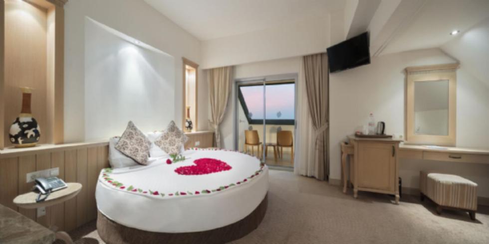 Saphir Resort & Spa luksusa numurs ar apaļu gultu, romantisku dekoru un balkonu — gaišs interjers pāriem