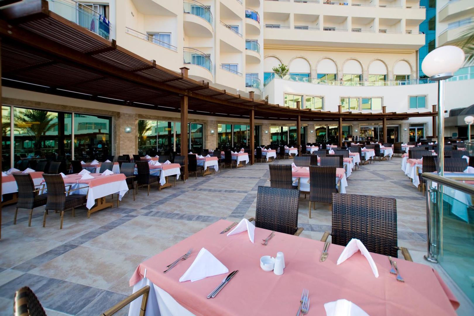 Saphir Resort & Spa āra terases restorāns ar skatu uz viesnīcas ēku un balkoniem vakara gaismā