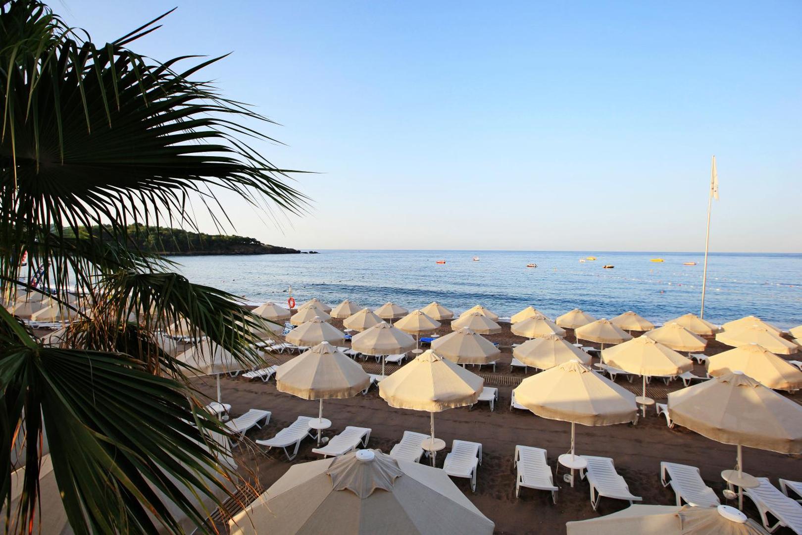 Saphir Resort & Spa privātā smilšu pludmale ar saulessargiem un gultām pie Vidusjūras Alānijā, Turcijā