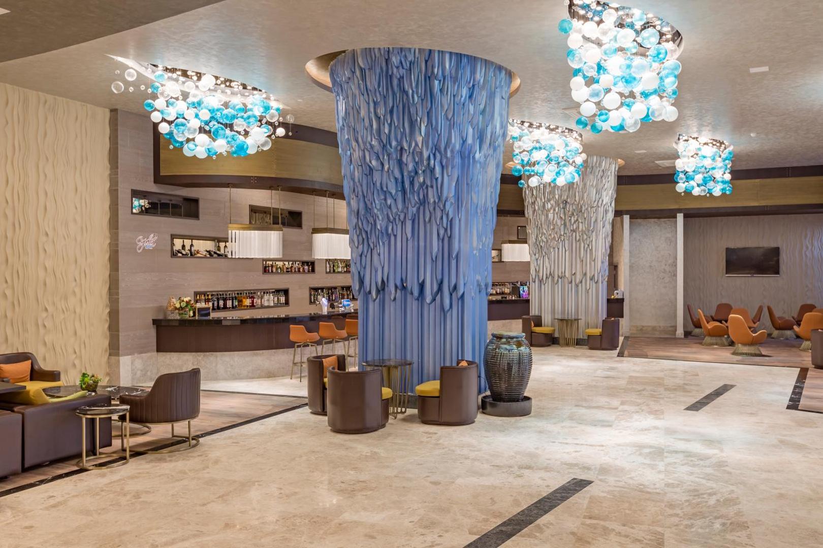Royal Seginus lobby bārs ar modernām zilām dekorācijām, mīkstajiem krēsliem un plašu dzērienu izvēli viesnīcas vestibilā