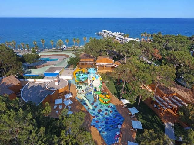 Rixos Sungate viesnīcas panorāmas skats no putna lidojuma — bērnu akvaparks, priežu mežs un zilā Vidusjūra piekrastē