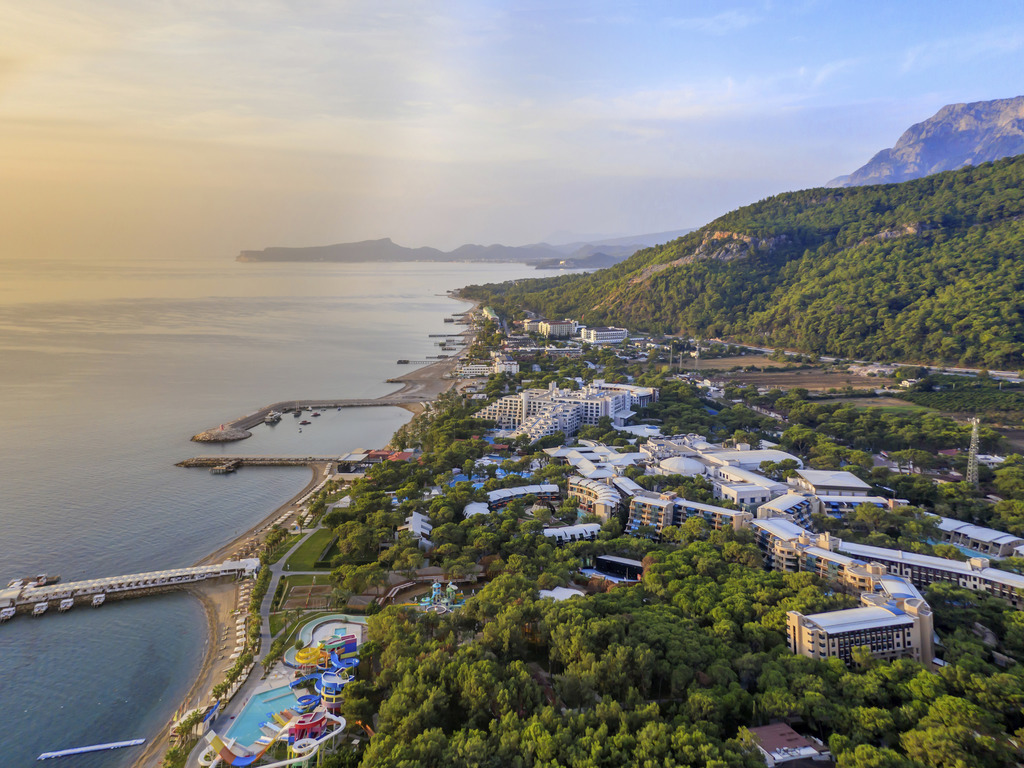 Rixos Sungate panorāmas skats no putna lidojuma Kemeras piekrastē — plaša viesnīcas teritorija starp Vidusjūru un priežu klātiem kalniem