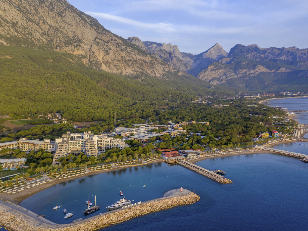 Rixos Sungate plašs ainavas skats uz viesnīcu, jahtu piestātni un iespaidīgajām Tauru kalnu virsotnēm Antālijas piekrastē