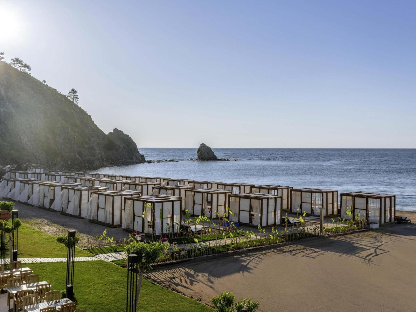 Rixos Premium Tekirova privātie pludmales bungalo un atpūtas nojumes smilšu pludmalē pie kalna pakājes
