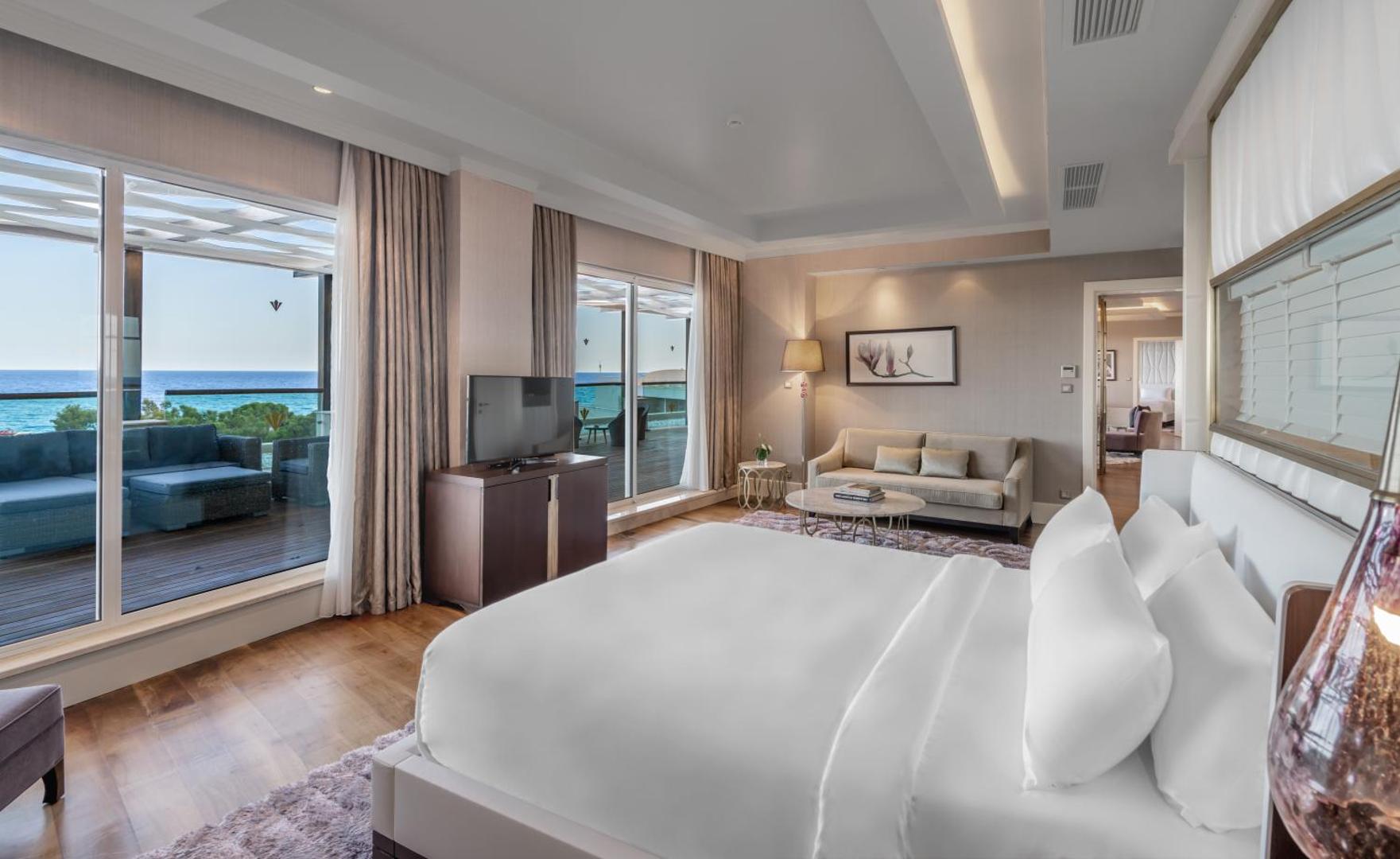 Rixos Premium Tekirova luksusa numurs ar atpūtas zonu, lielu gultu un plašu terasi ar skatu uz jūru