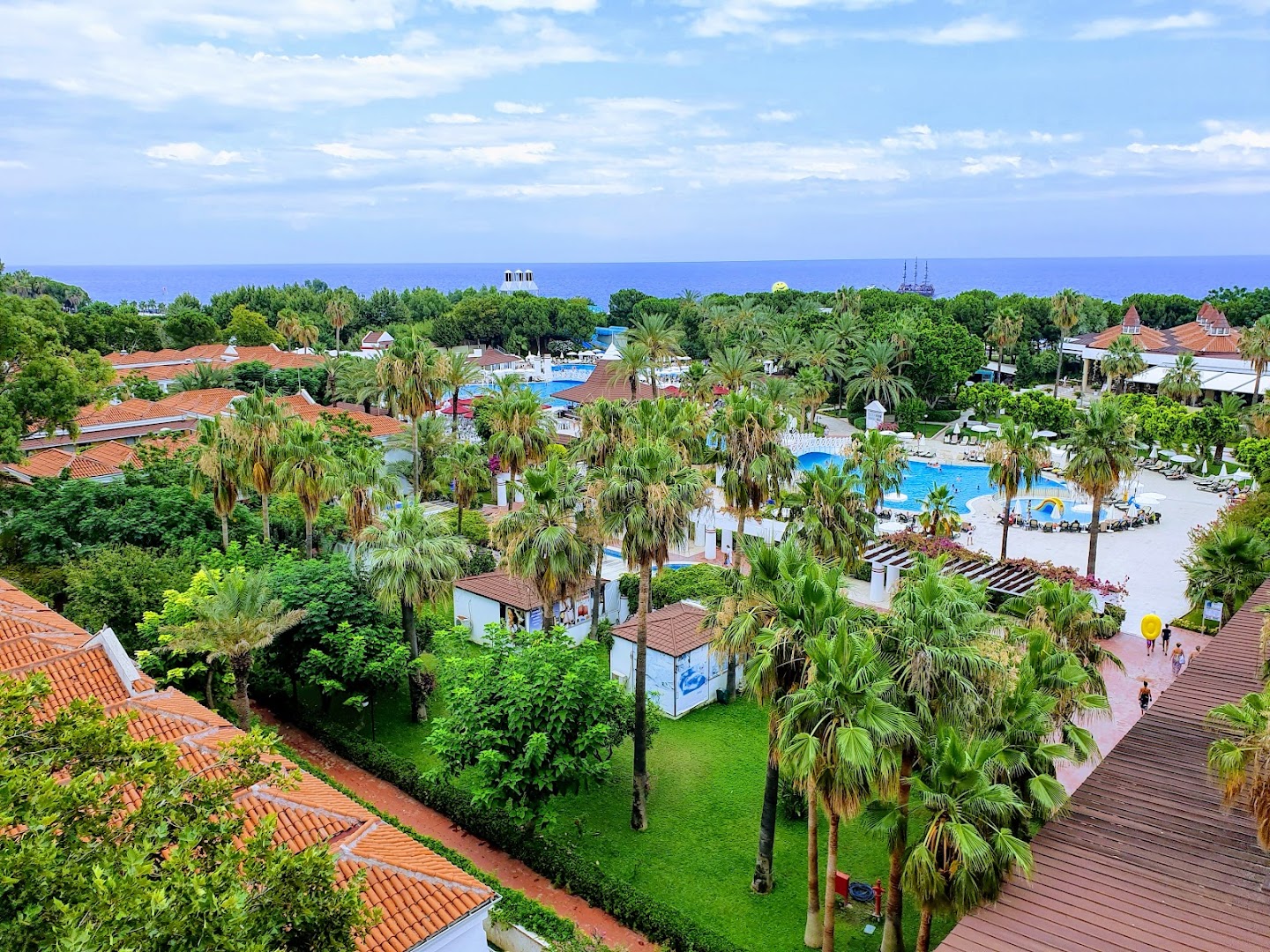 Swandor Hotels & Resorts plašā teritorija ar palmām, baseiniem un sarkanu dakstiņu jumtiem pie Vidusjūras krasta Antaljas reģionā