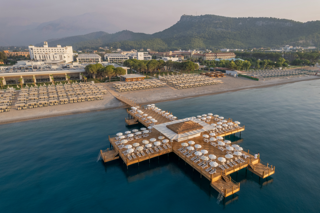 Aerofoto skats uz Swandor Hotels & Resorts Kemeras piekrastē ar plašu koka piestātni, pludmali un kalniem fonā
