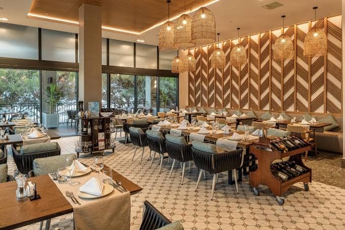 Swandor Hotels & Resorts a la carte restorāns ar pītiem gaismekļiem, koka sienu apdari un eleganti klātiem galdiem