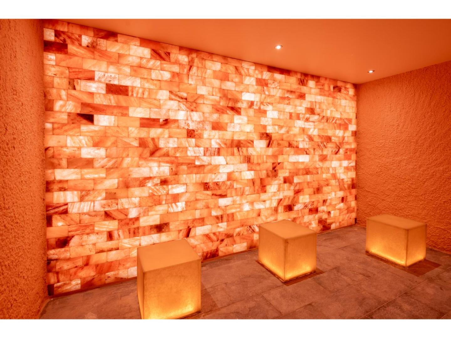 Swandor Hotels & Resorts sāls istaba ar izgaismotu sāls ķieģeļu sienu un ērtiem sēdekļiem — veselības procedūras spa zonā