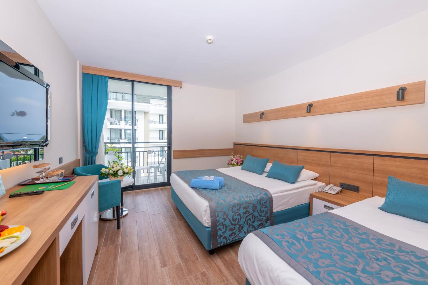 Meryan Hotel numurs ar divguļamo un vienguļamo gultu, ziliem akcentiem un skatu uz viesnīcas teritoriju
