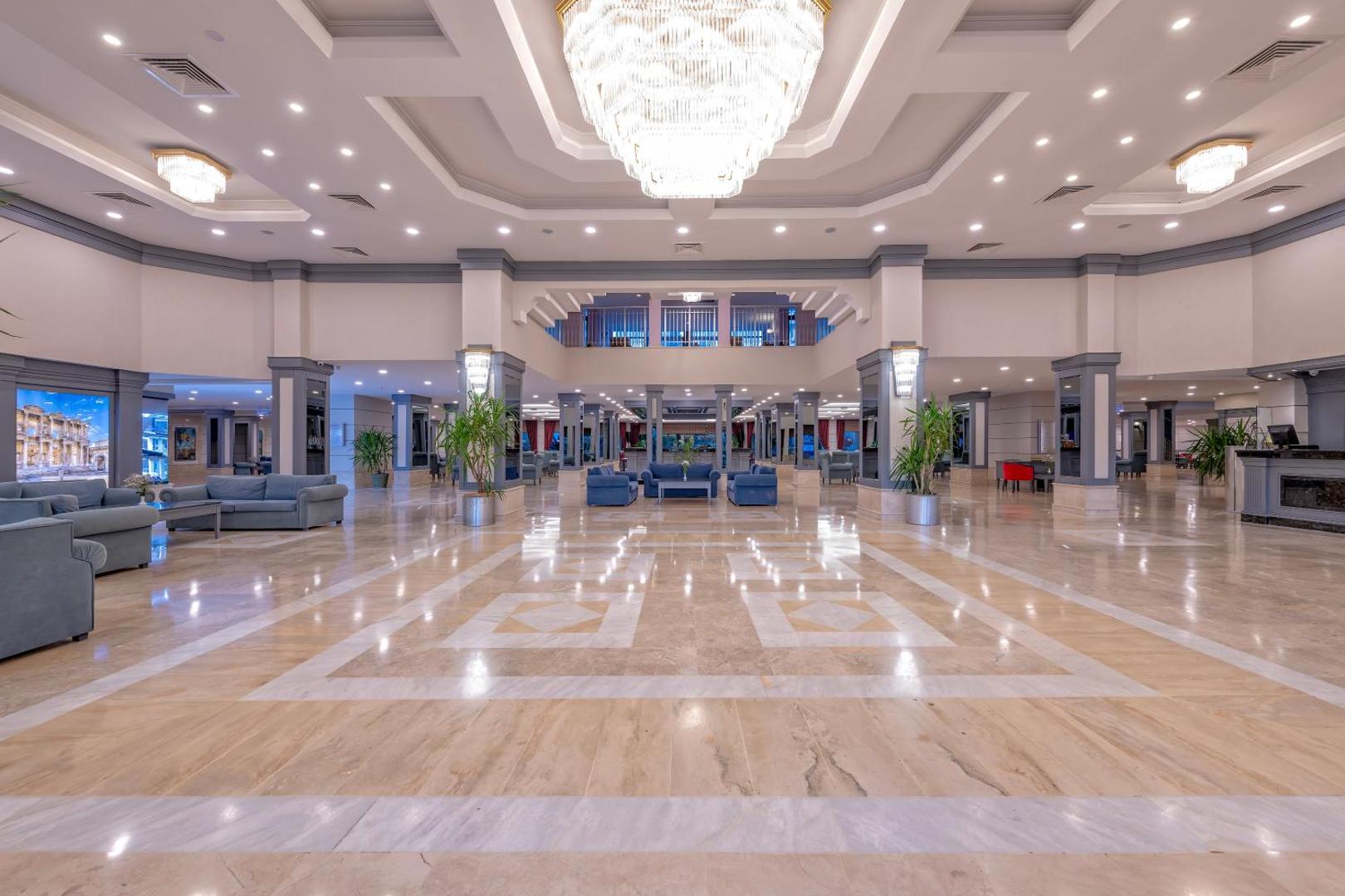 Meryan Hotel plašais un gaišais lobby vestibils ar marmora grīdu, atpūtas zonām un greznām lustrām