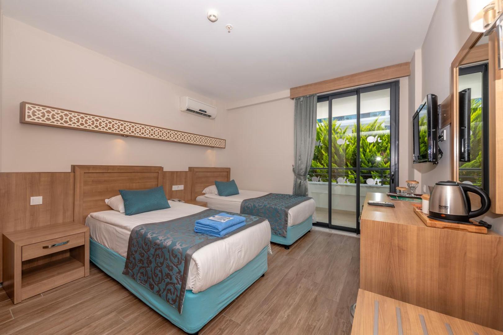 Meryan Hotel gaišs standarta numurs ar divām atsevišķām gultām, koka mēbelēm un balkonu Alānijas reģionā, Turcijā