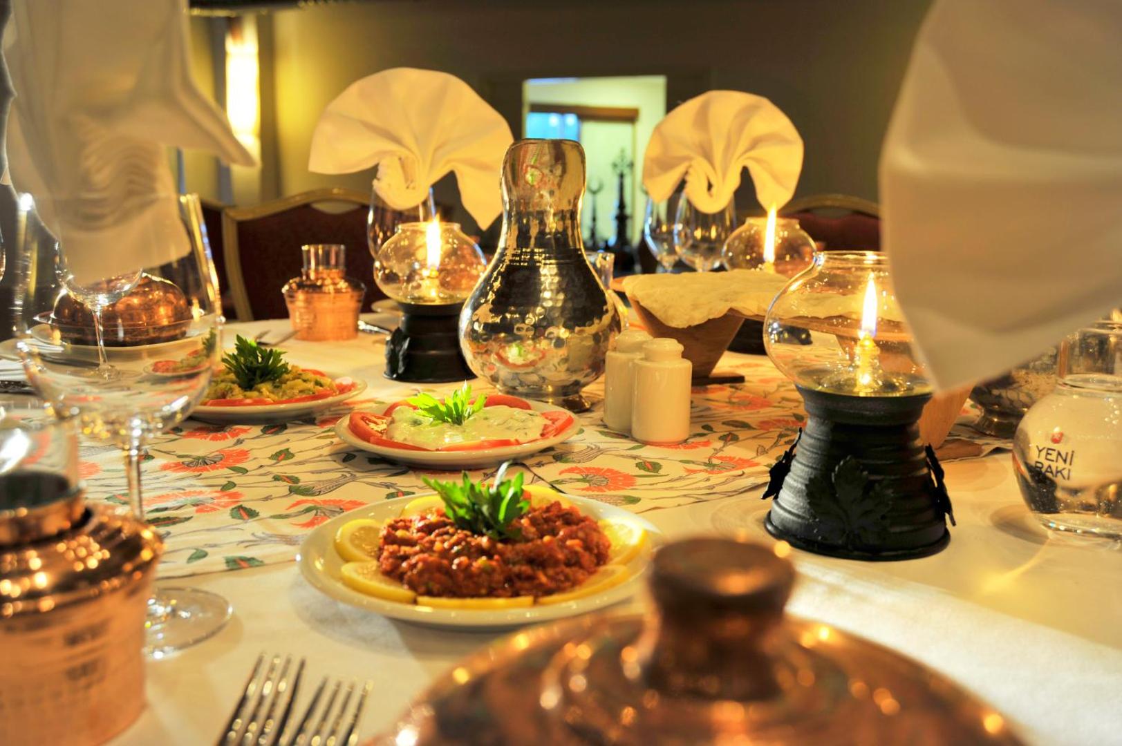 Marti Myra Hotel restorāna galda klājums ar tradicionālām uzkodām, svecēm un dekoratīviem traukiem vakariņu laikā