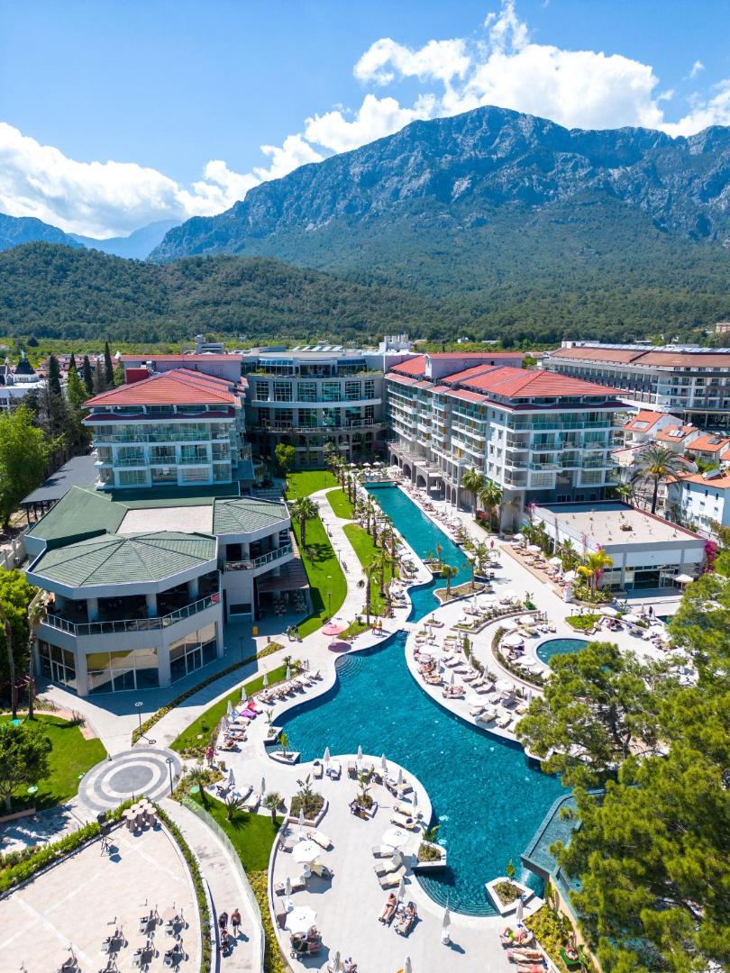 Akra Kemer viesnīcas teritorija no putna lidojuma – baseini, ēkas un apkārtējie kalni Kemeras reģionā
