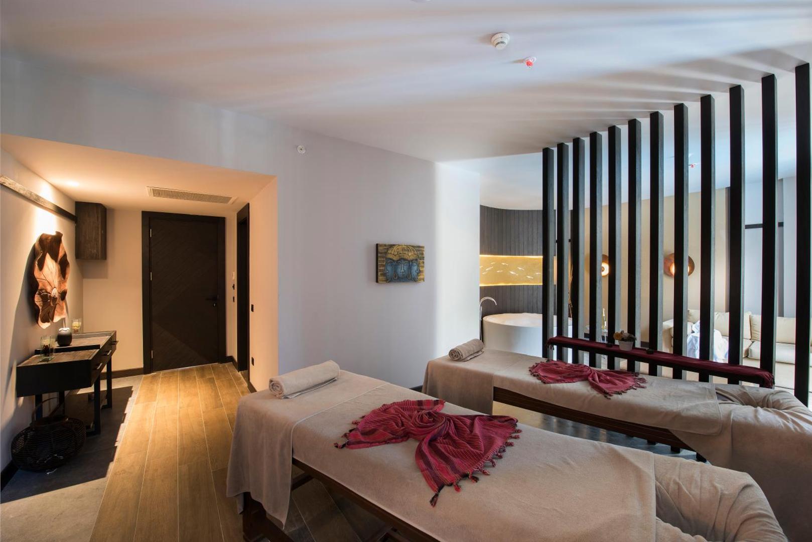 Akra Kemer SPA centra masāžas telpa ar divām kušetēm, siltu apgaismojumu un modernu interjeru relaksācijai