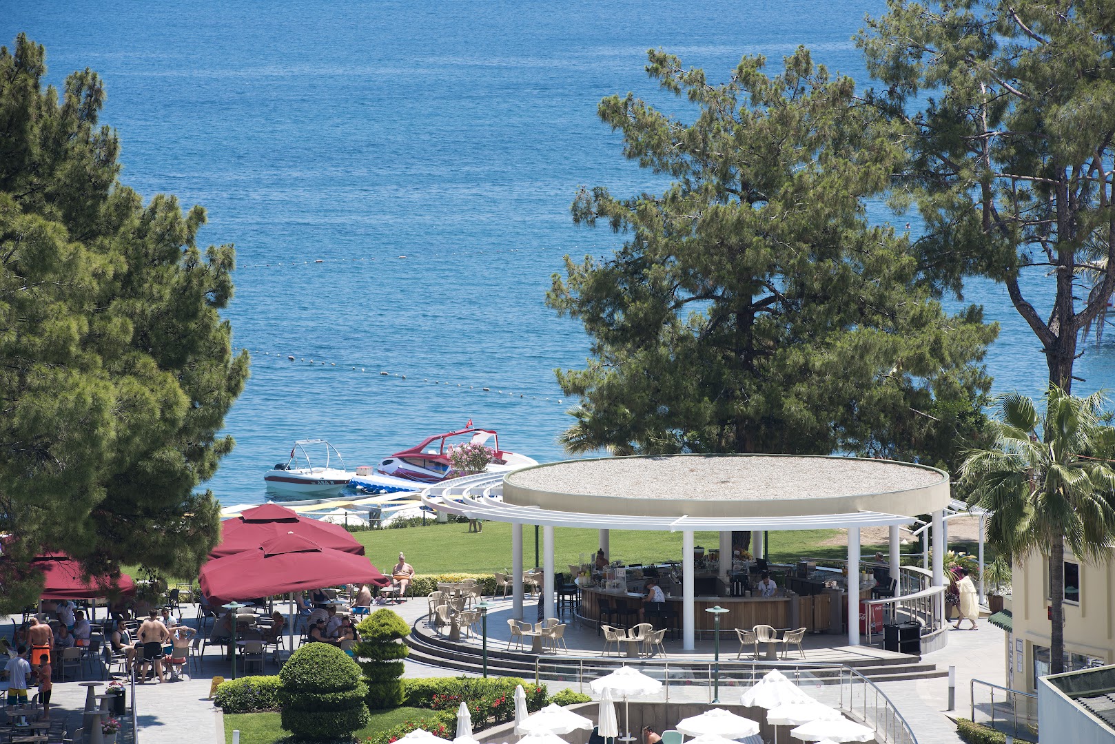 Akra Kemer āra bārs piekrastē ar skatu uz Vidusjūru, priežu ieskauts, ar atpūtas krēsliem un saulessargiem