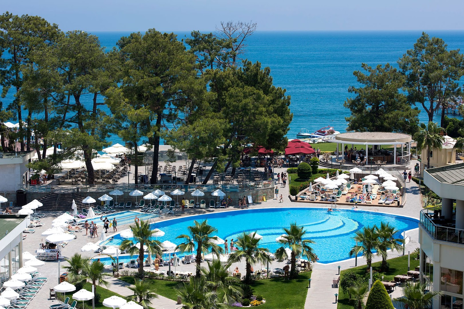Akra Kemer viesnīcas teritorijas skats no augšas ar baseinu, bāru, priežu mežu un Vidusjūras piekrasti Kemeras reģionā