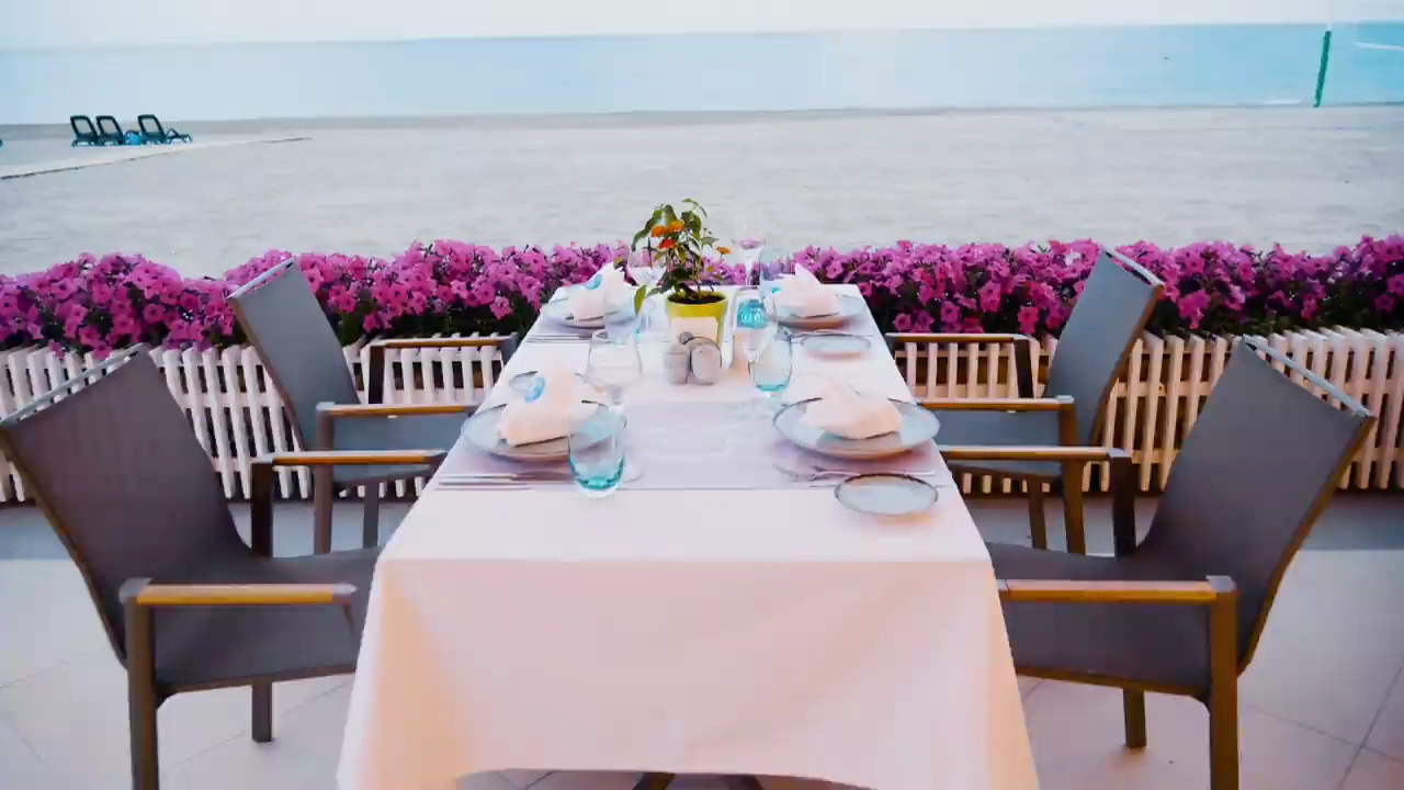 IC Hotels Santai Family Resort restorāna galdiņš ar skatu uz jūru Belekā — eleganti klāts galds piekrastē ar ziedu dekorācijām