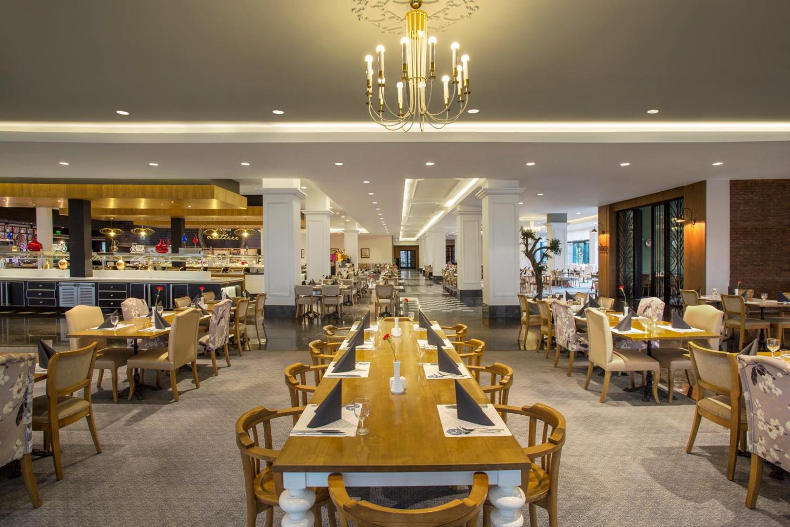 IC Hotels Santai Family Resort galvenais restorāns ar elegantiem galdiem, klasisku interjeru un lielu lustru Belekā, Turcijā
