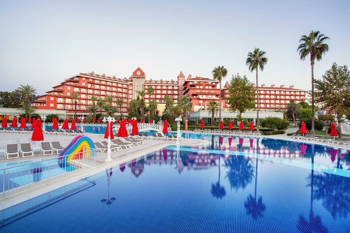 IC Hotels Santai Family Resort galvenā ēka sarkanos toņos pie liela baseina ar bērnu slidkalniņu un saulessargiem