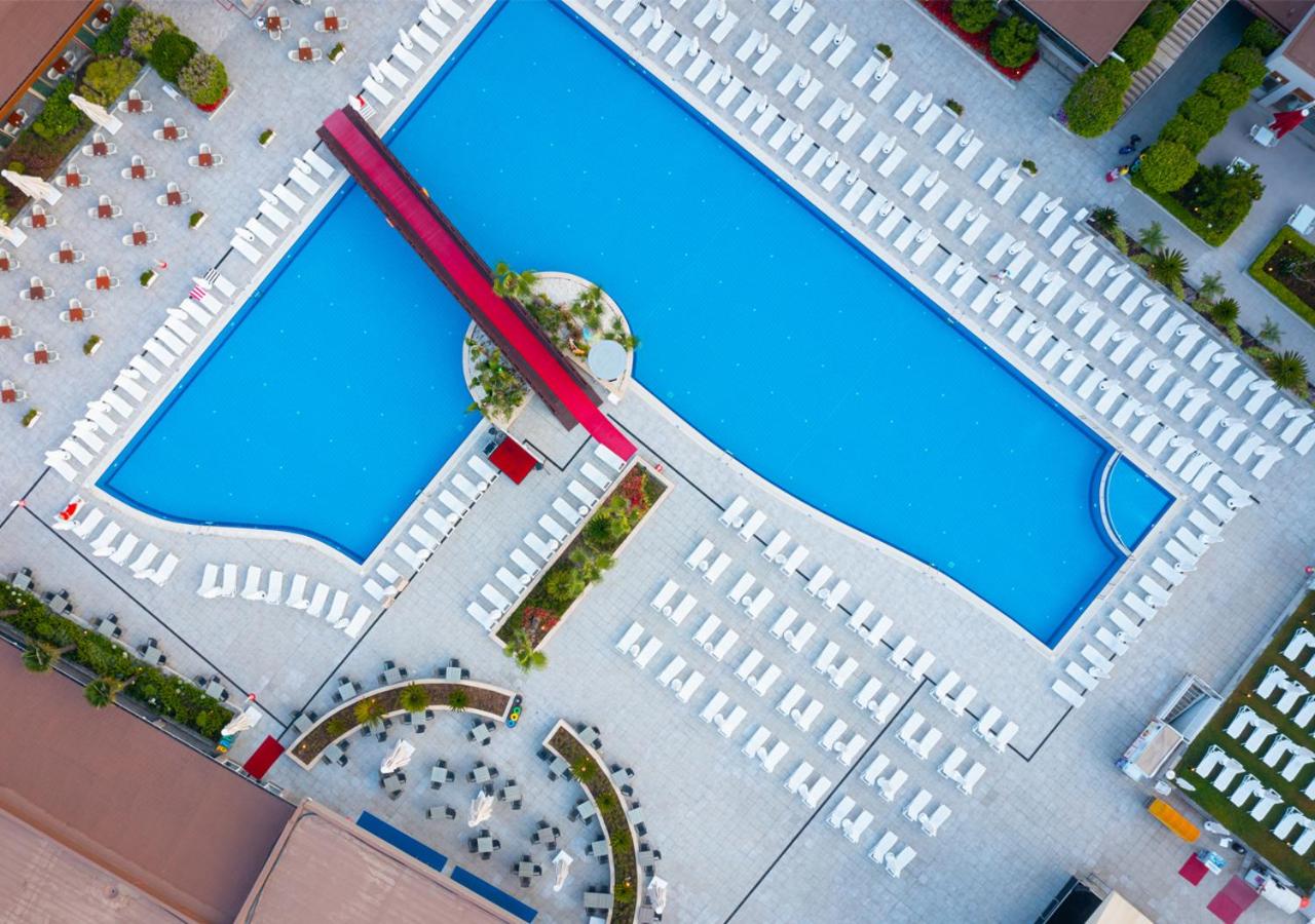 Grand Park Lara galvenā baseina skats no augšas ar tiltiņu, atpūtas krēsliem un āra kafejnīcas galdiņiem