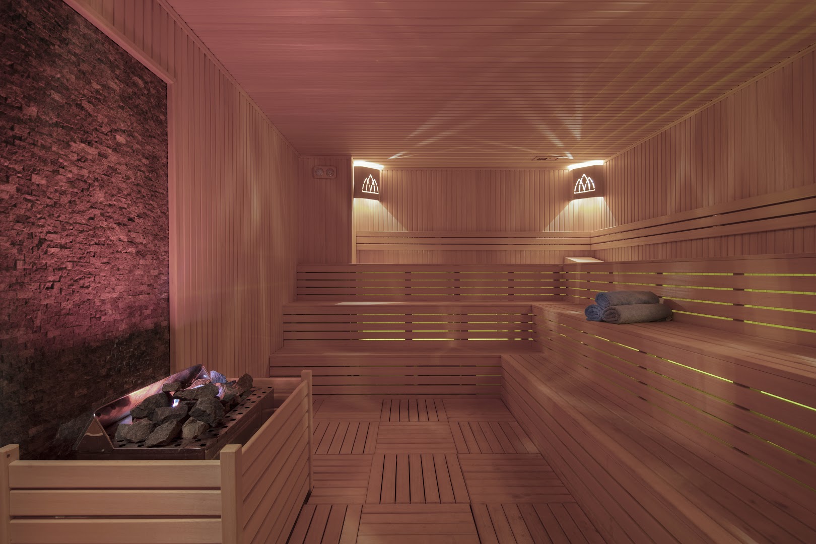 Granada Luxury Beach spa centra sauna ar koka apdari, akmens sienas elementu un siltu apgaismojumu relaksācijai