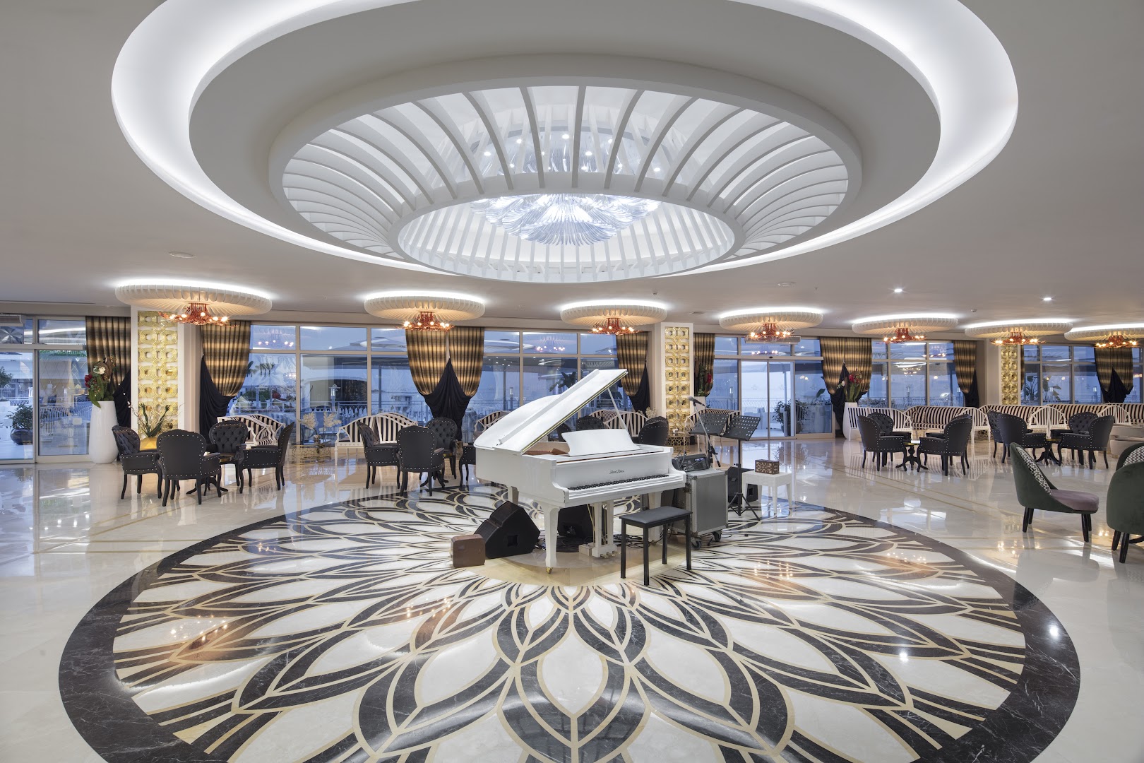 Granada Luxury Beach plašā lobby zāle ar baltu flīģeli centrā, greznu griestu dizainu un atpūtas zonām pie lieliem logiem