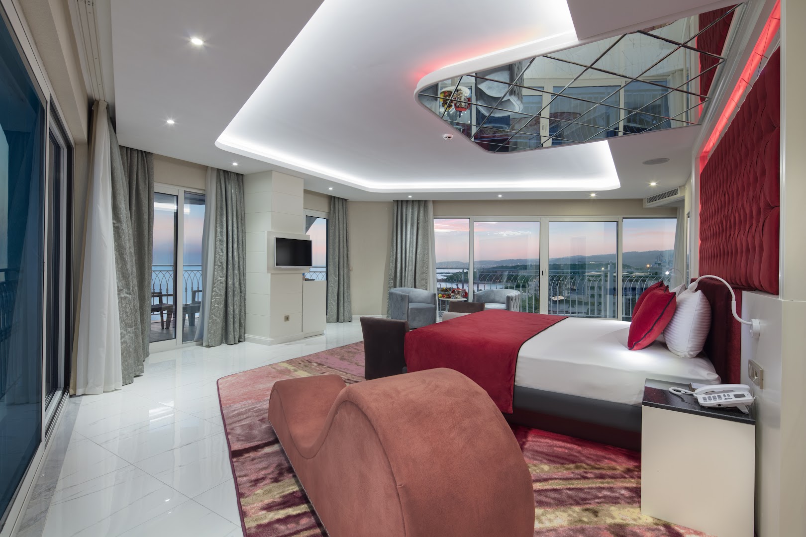 Plašs Granada Luxury Beach viesnīcas luksusa numurs ar panorāmas logiem un dizaina mēbelēm Alānijas piekrastē saulrieta laikā