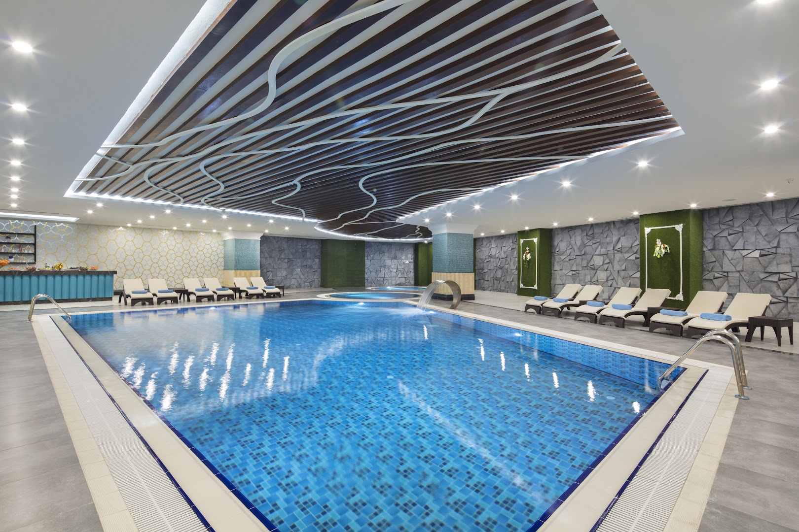 Granada Luxury Beach iekštelpu baseins ar modernu griestu dizainu, strūklaku un atpūtas krēsliem spa centrā