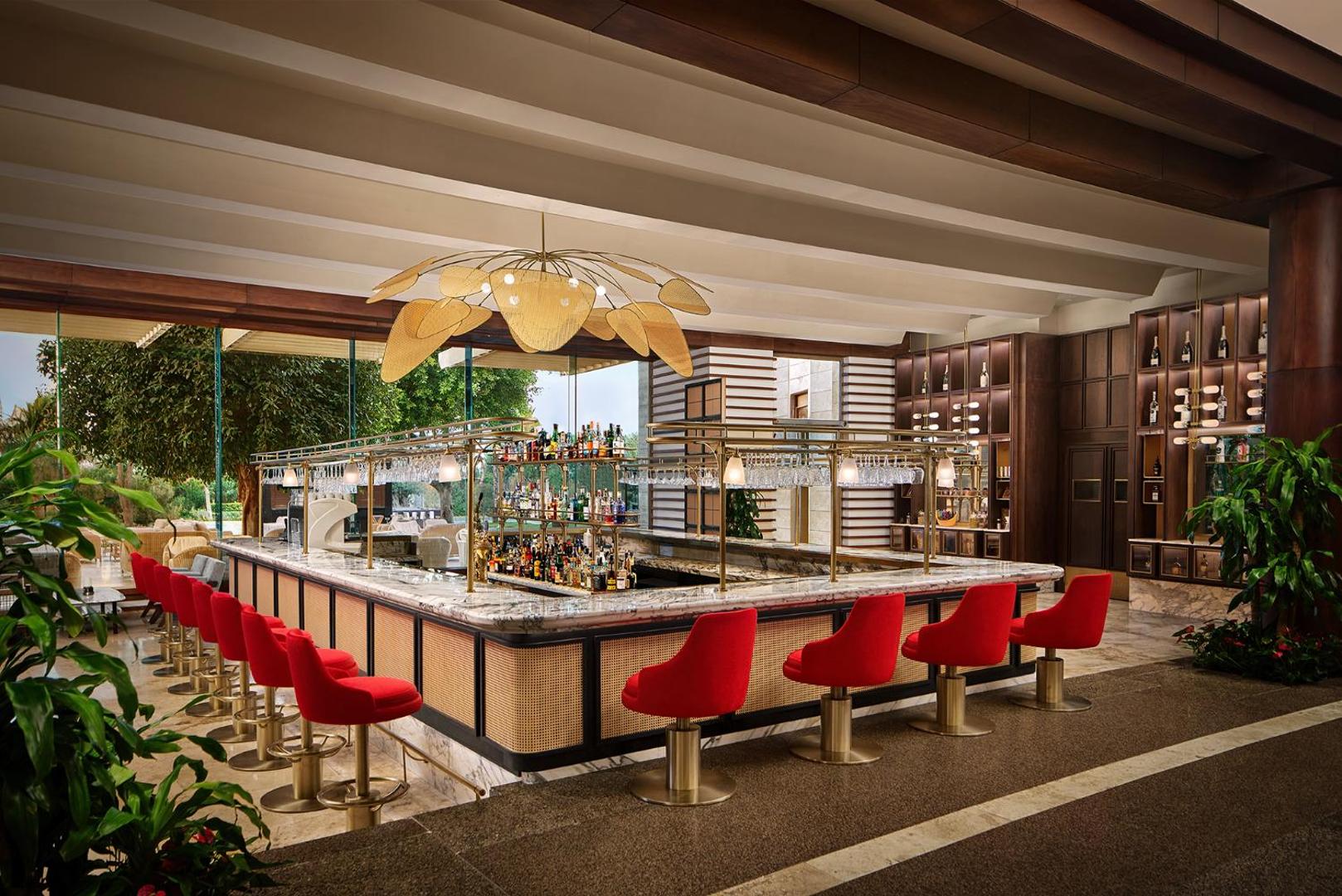 Gloria Serenity Resort bārs ar sarkanām mīkstajām mēbelēm, marmora leti un plašu dzērienu izvēli viesnīcas lobby zonā