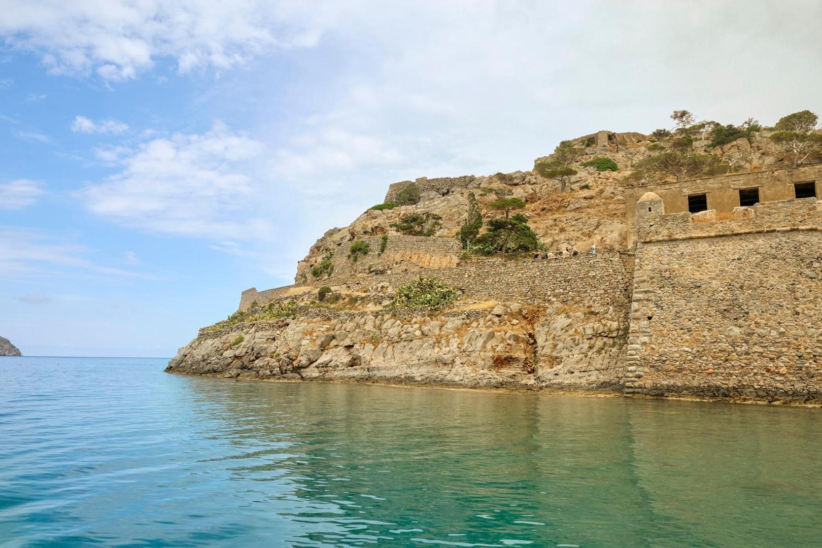 Skats no jūras uz vēsturisko Spinalongas salu netālu no Zeus Eleva Mirabello Bay kūrorta Krētā — akmens nocietinājumi un klintis