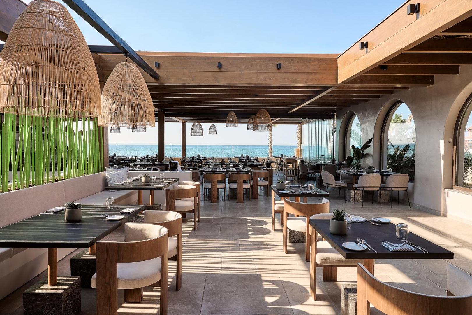 Stella Palace Aqua Park Resort moderns āra restorāns ar dizaina lampām, koka mēbelēm un skatu uz zilo jūru
