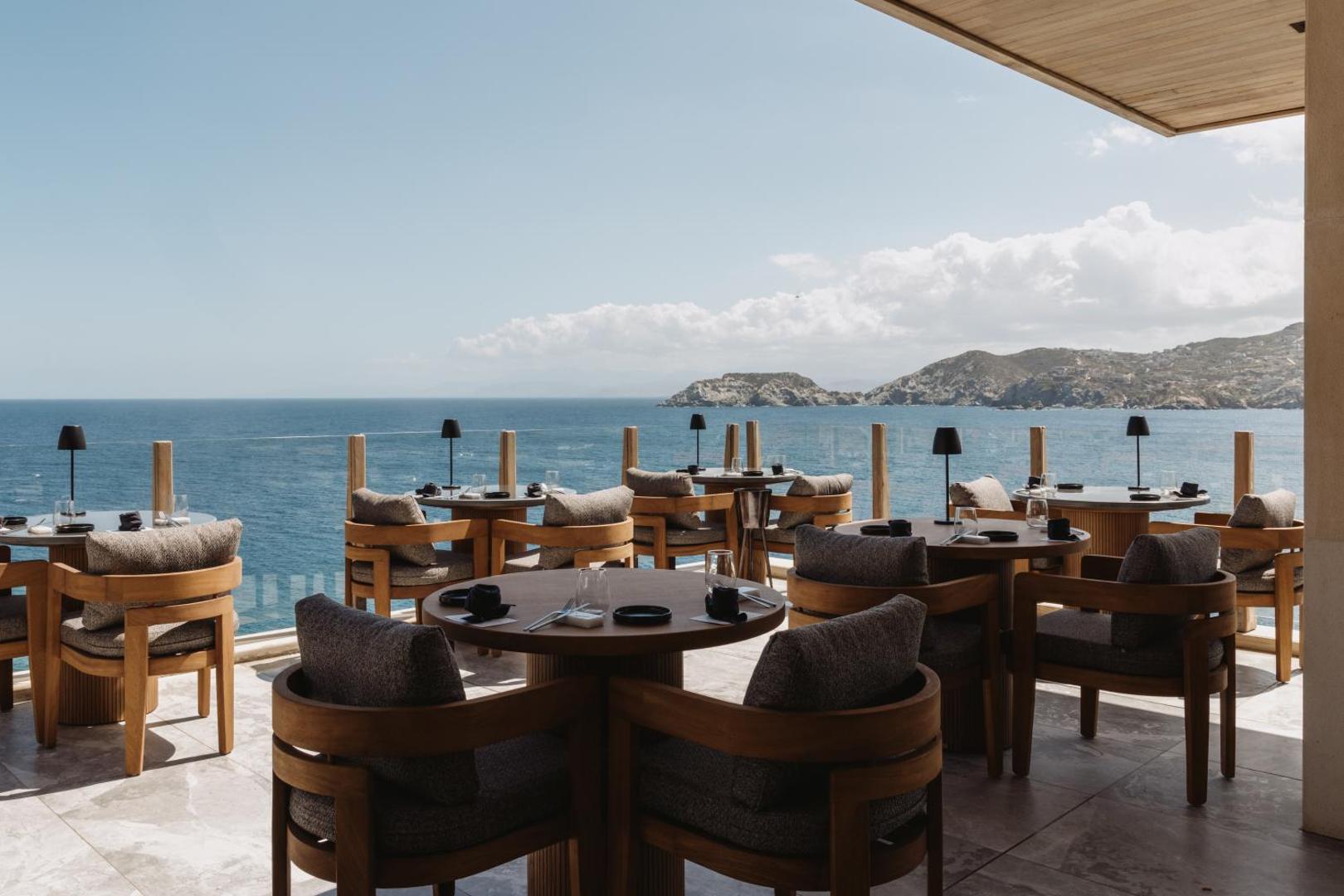 Seaside A Lifestyle Resort restorāna terase ar koka mēbelēm un stikla margām, no kuras paveras skats uz jūru